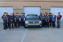  A group of students and adults standing around a Volkswagen Tiguan